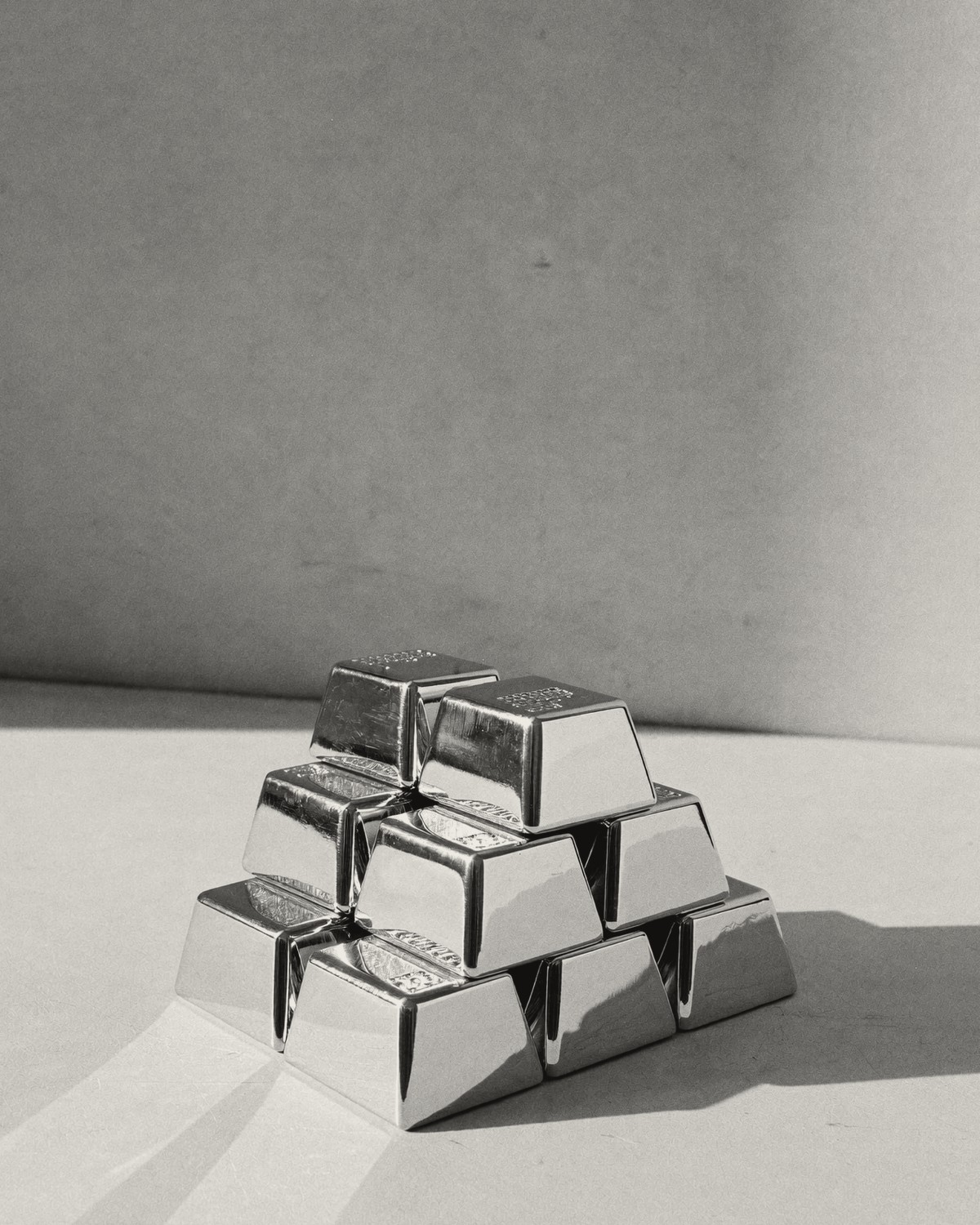 A small stacked pyramid of silver bullion bars in raking light.