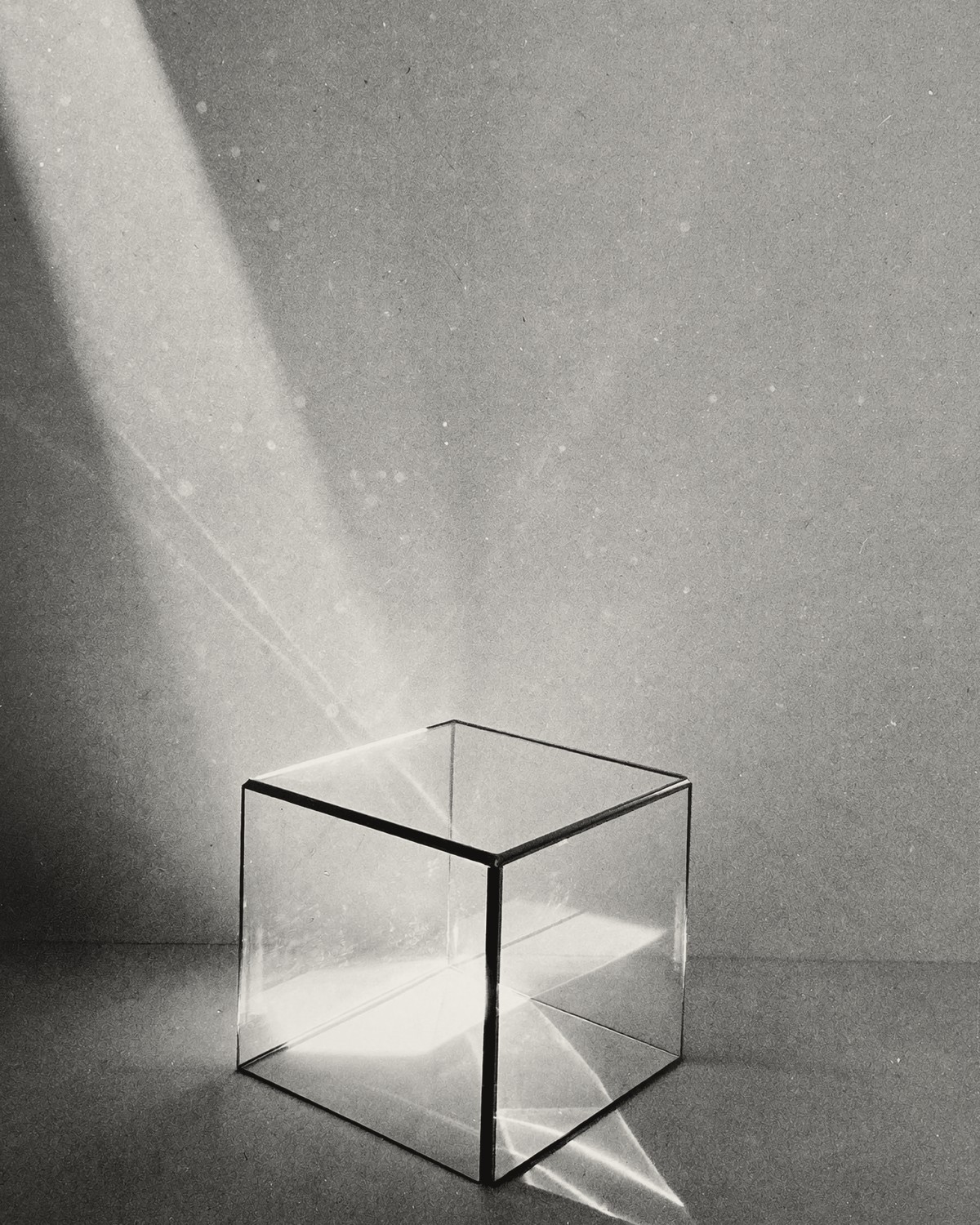 An empty glass cube on a table, a beam of light splitting as it passes through.